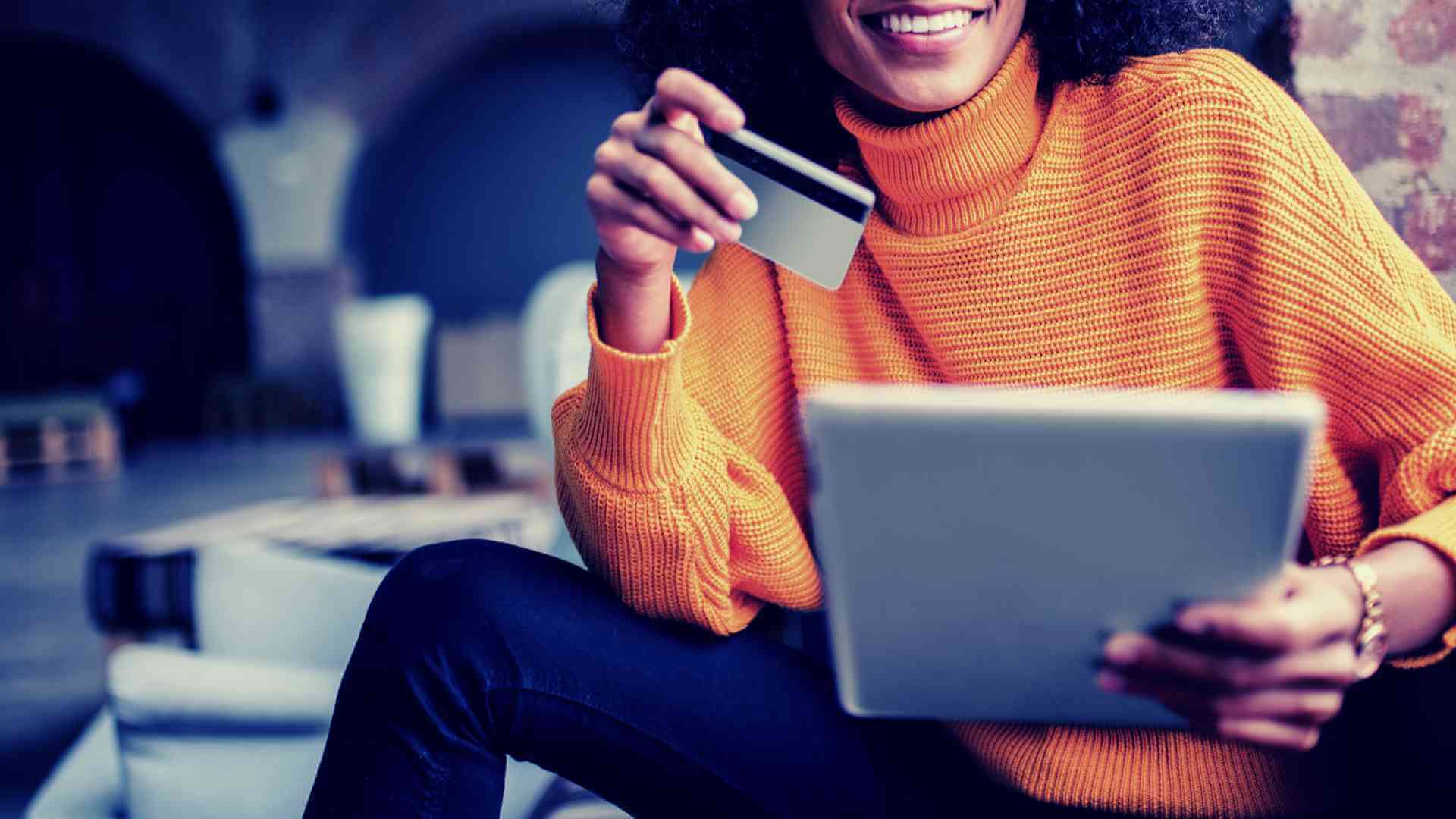 woman holding tablet and credit card in each hand